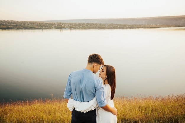 Vue arrière d'un jeune couple romantique debout sur la rive profitant de beaux moments
