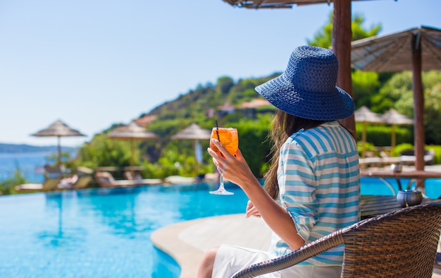 Vue arrière de la jeune femme assise dans un café tropical près de la piscine