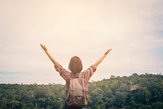 Vue arrière d'une jeune femme avec les bras levés contre le ciel