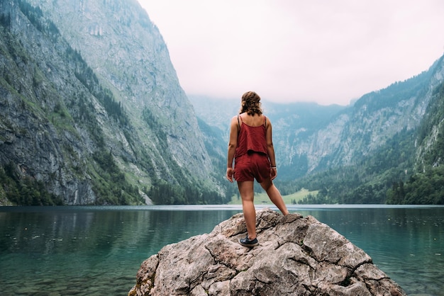Photo vue arrière d'une jeune femme debout au lac contre la montagne