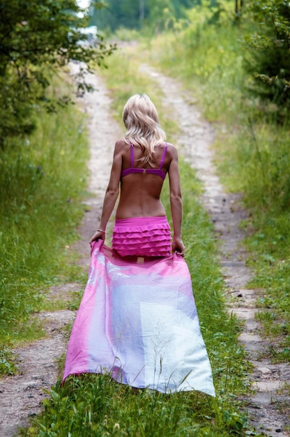 Photo vue arrière d'une jeune femme marchant sur un champ herbeux