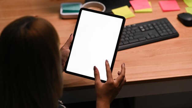 Vue arrière jeune femme naviguant sur internet avec tablette numérique.