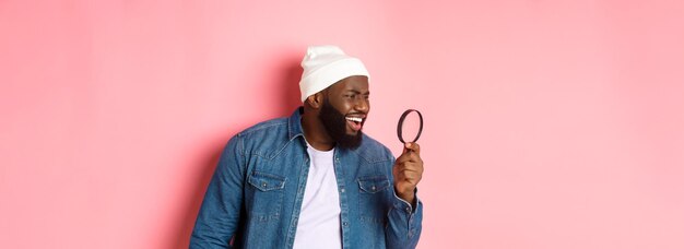 Vue arrière d'une jeune femme portant des lunettes de soleil alors qu'elle se tient contre un fond rose