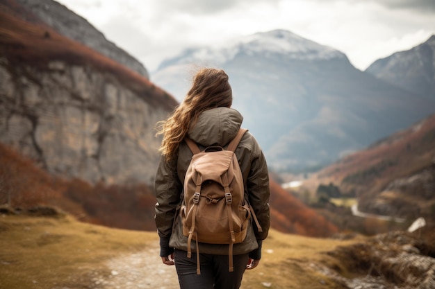 Photo vue d'arrière d'une jeune femme avec un sac à dos faisant de la randonnée dans les montagnes une randonneuse qui marche dans les monts sans visages visibles fond naturel généré par l'ia