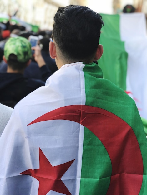 Photo vue arrière d'un jeune homme portant un drapeau