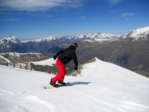 Vue arrière d'un jeune homme en snowboard contre le ciel