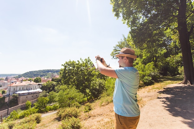 Vue arrière d'un jeune touriste prenant une photo avec un smartphone devant la ville