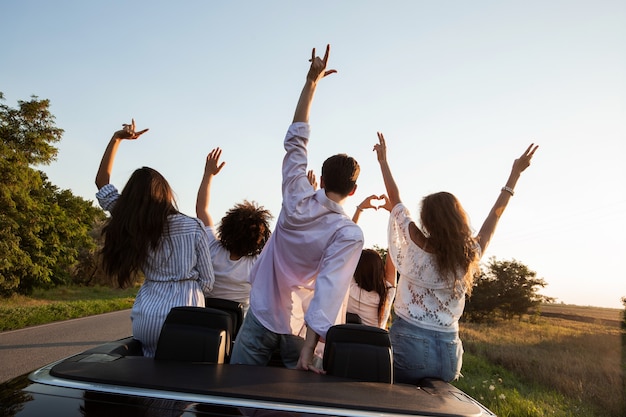 Vue arrière. Des jeunes hommes sont assis et se tiennent la main dans un cabriolet noir sur la route de campagne par une journée ensoleillée. .