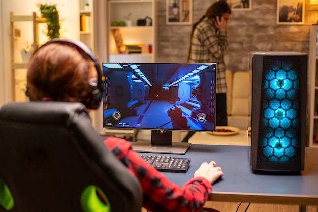 Photo vue arrière d'une joueuse jouant sur un ordinateur puissant tard dans la nuit dans le salon.