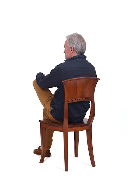 Vue arrière et latérale d'un homme assis sur une chaise jambes croisées sur fond blanc