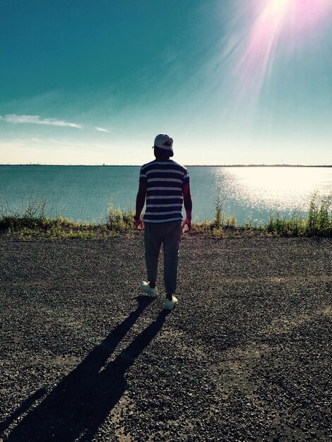 Photo vue arrière à longueur complète d'un homme debout sur la plage contre le ciel