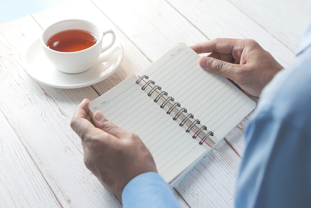 Vue arrière de la main de l'homme tournant une page d'un bloc-notes.