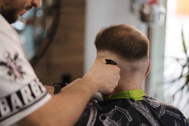 Vue arrière de la main humaine tenir la tondeuse et faire la coiffure pour le salon de coiffure homme