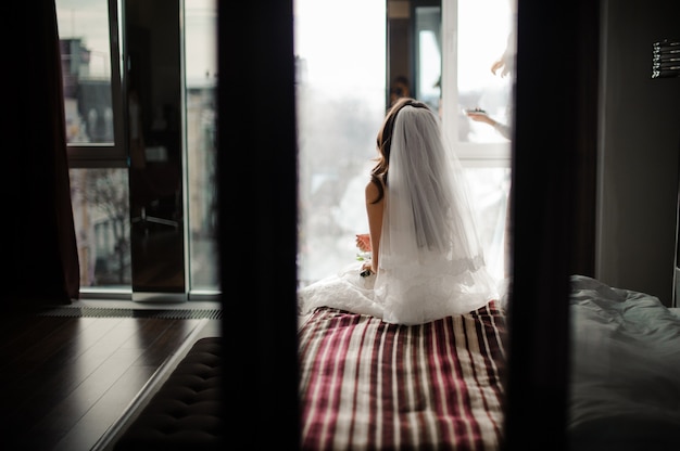 Vue arrière de la mariée en voile de mariage assis sur le lit