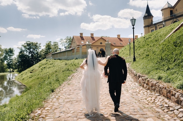 Vue arrière. les mariés marchent le long de la route de pierre vers le château
