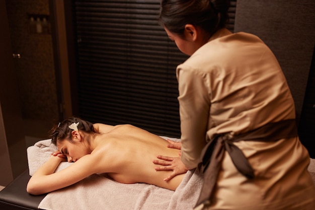 Vue arrière d'une masseuse massant le dos d'une jeune femme