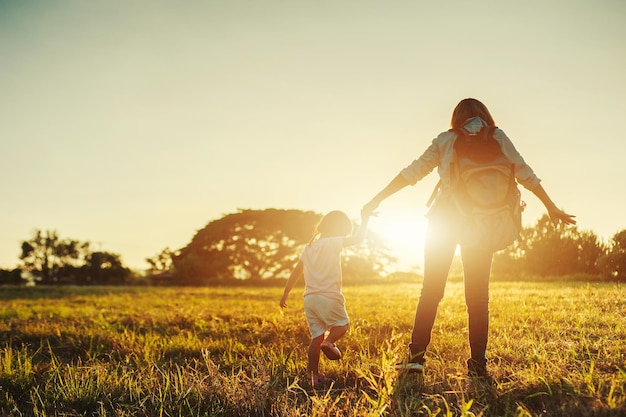 Vue arrière d'une mère et d'une fille sur le champ au coucher du soleil