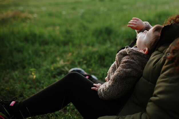 Photo vue arrière d'une mère et d'une fille sur l'herbe contre le ciel