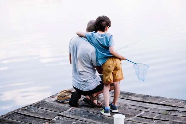 Vue arrière d'un pêcheur avec son fils pêchant sur le lac