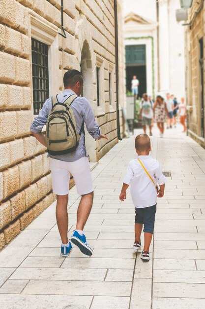 Photo vue arrière d'un père et de son fils en marchant dans la rue