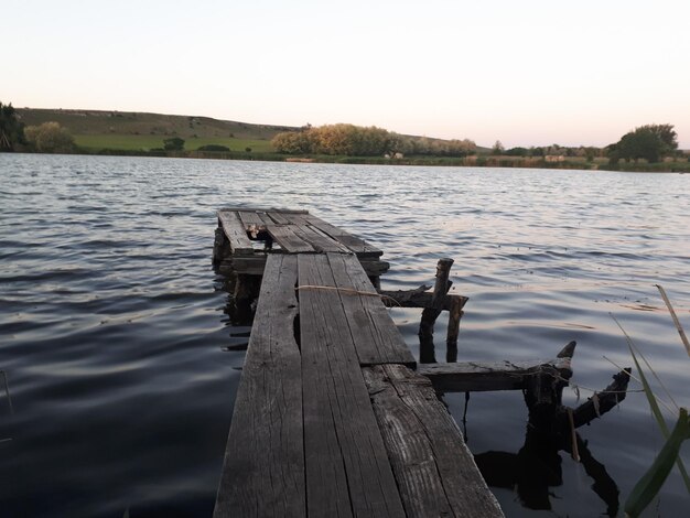 Vue arrière d'un père avec son petit fils pêchant assis sur une jetée en bois au bord de l'étang