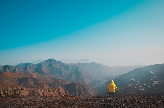 Vue arrière d'une personne accroupi sur une montagne contre le ciel