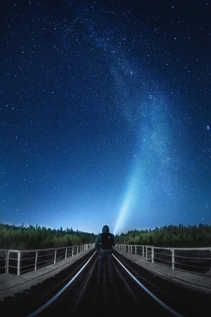 Photo vue arrière d'une personne debout sur la route contre le ciel étoilé la nuit