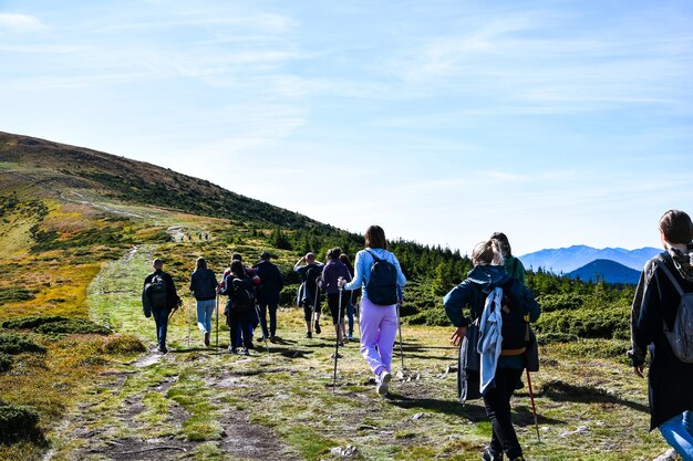 Vue arrière des personnes faisant de la randonnée dans les montagnes. Groupe de personnes marchant vers l'avant du col. Groupe de randonneurs marchant dans les montagnes