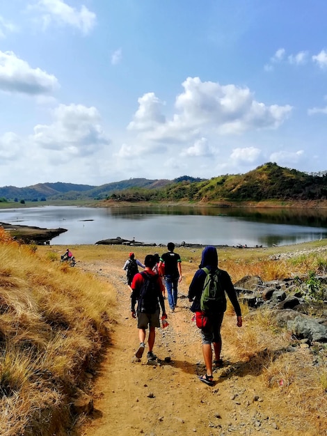 Photo vue arrière de personnes marchant sur un sentier près du lac