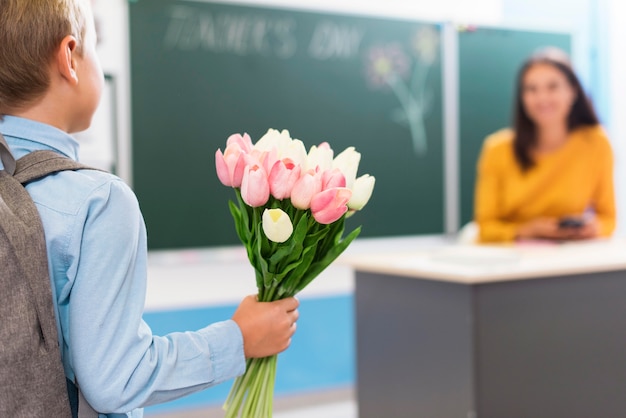 Vue arrière petit garçon tenant un bouquet de fleurs pour son professeur