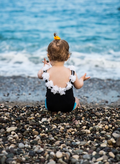 Photo vue arrière d'une petite fille assise sur la plage