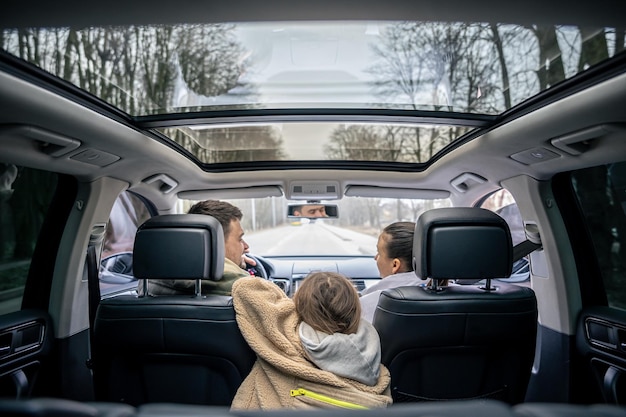 Vue arrière petite fille assise sur le siège arrière de la voiture pendant un voyage en famille