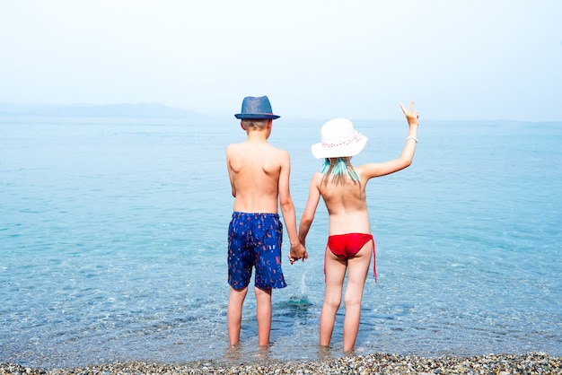 Vue arrière de la petite fille et garçon tenant par la main au bord de la mer.