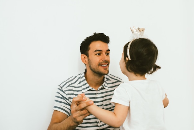 Vue arrière de la petite fille mignonne ludique portant la couronne dansant avec papa et se sentir heureuse pour sa surprise d'anniversaire sur fond blanc Portrait horizontal de la fille et du père célébrer les vacances