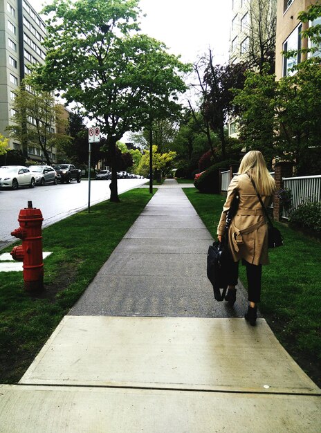 Photo vue arrière pleine longueur d'une femme d'affaires avec une mallette marchant sur le trottoir de la ville