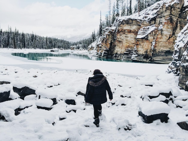 Vue arrière pleine longueur d'une femme marchant sur la neige
