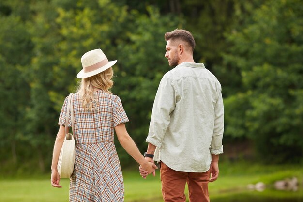 Vue Arrière Portrait De Couple Adulte Romantique Main Dans La Main En Marchant Vers La Rivière Dans Un Paysage De Campagne Rustique