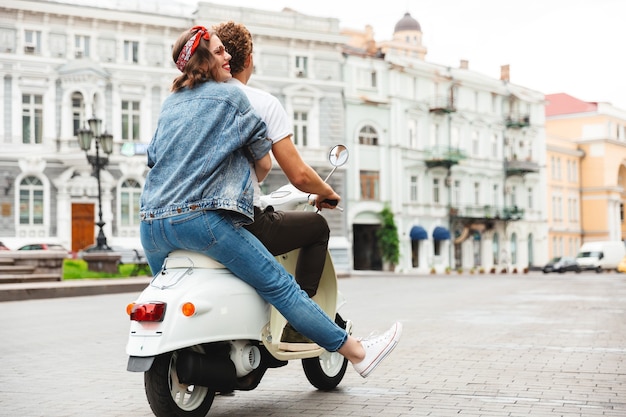 Vue arrière portrait d'un jeune couple moderne à cheval sur une moto ensemble à la rue de la ville