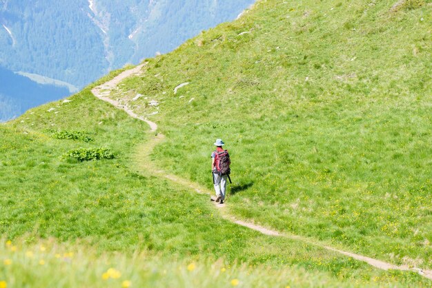 Photo vue arrière d'un randonneur avec un sac à dos marchant sur un sentier de montagne