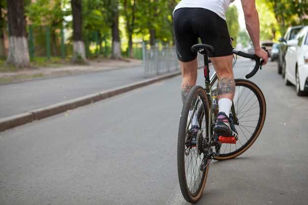 Vue arrière recadrée d'un cycliste méconnaissable faisant du vélo sur la route