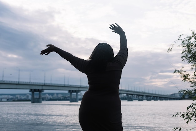 Vue arrière de la silhouette de femme multiculturelle bouclée regardant l'horizon de l'eau mer plage et ciel espace de copie positif du corps