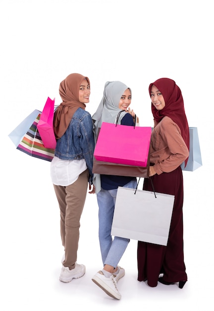 Vue arrière de trois femmes hijab portant un sac en papier après avoir magasiné ensemble