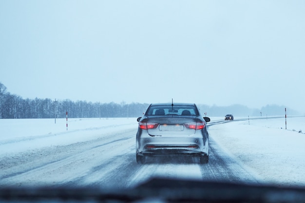 Photo vue arrière de la voiture sur la route d'hiver enneigée