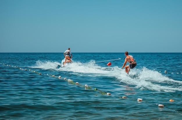 Vue arrière sur wakeboarder apprendre à rouler sur la mer en été journée ensoleillée wakeboard sur la plage