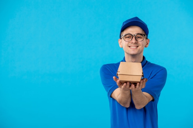 Vue avant de courrier masculin en uniforme avec colis de livraison sur un bleu