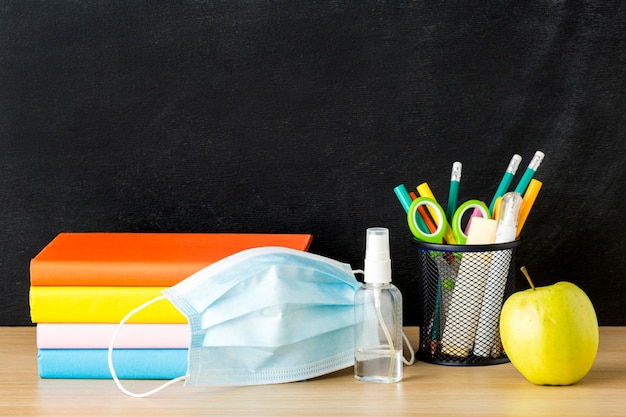 Vue avant du dos aux fournitures scolaires avec masque médical et livres