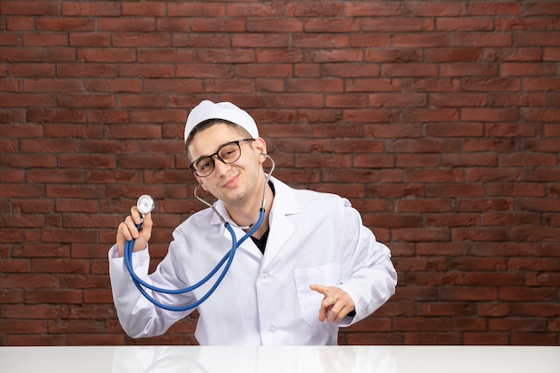 Vue avant de l'homme médecin en costume médical blanc avec stéthoscope