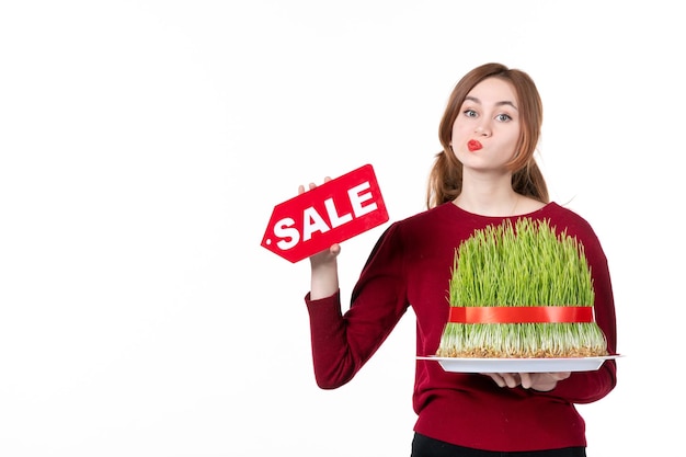 Vue avant jeune femme holding big novruz semeni et vente plaque signalétique sur fond blanc couleurs artiste ethnique concept shopping famille ethnique