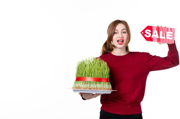 Vue avant jeune femme holding big novruz semeni et vente plaque signalétique sur fond blanc couleurs diner concept interprète shopping printemps ethnique