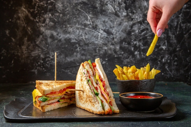 Vue avant de savoureux sandwichs au jambon avec frites surface sombre